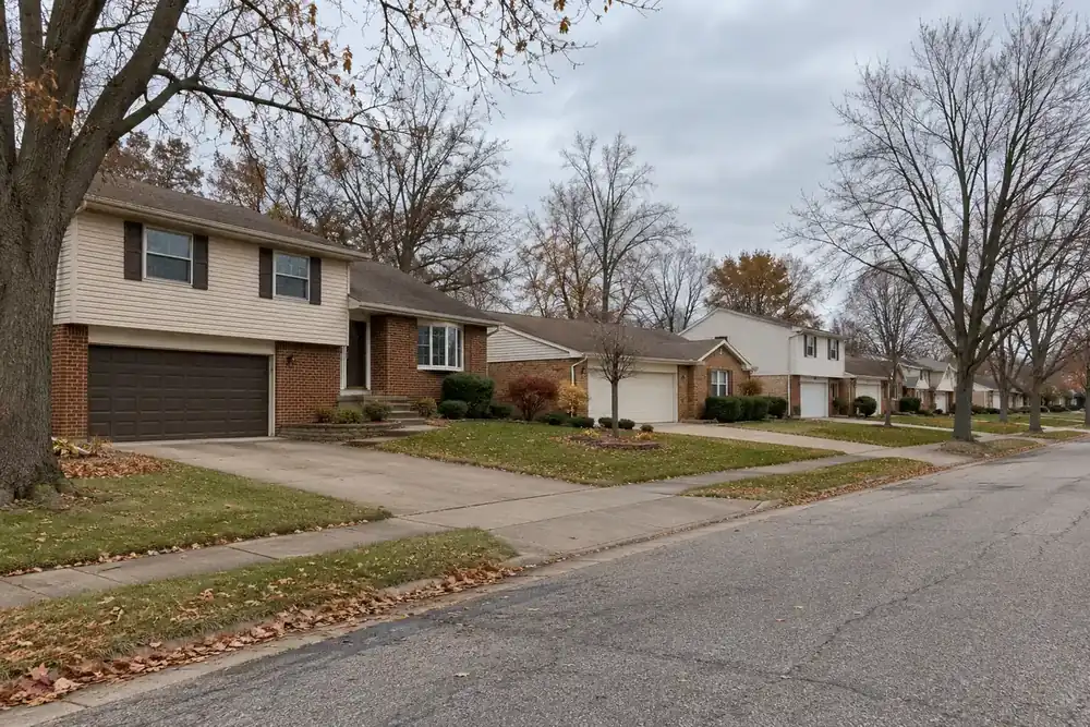 Quiet suburban street on an overcast autumn day with brick and vinyl homes and attached garages