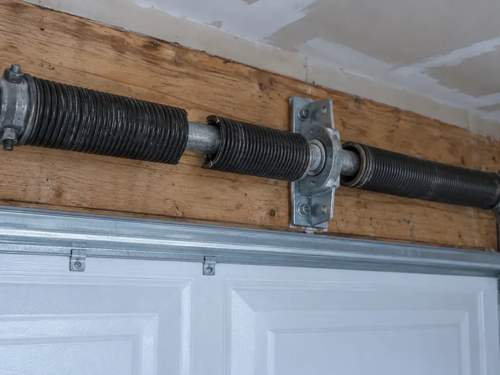 Broken torsion spring with a visible gap in the coil above the door