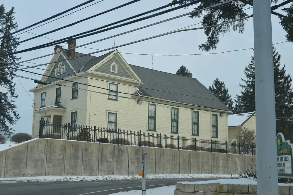The cream two-story Bath Township Hall above a stone wall in Bath Township, Ohio