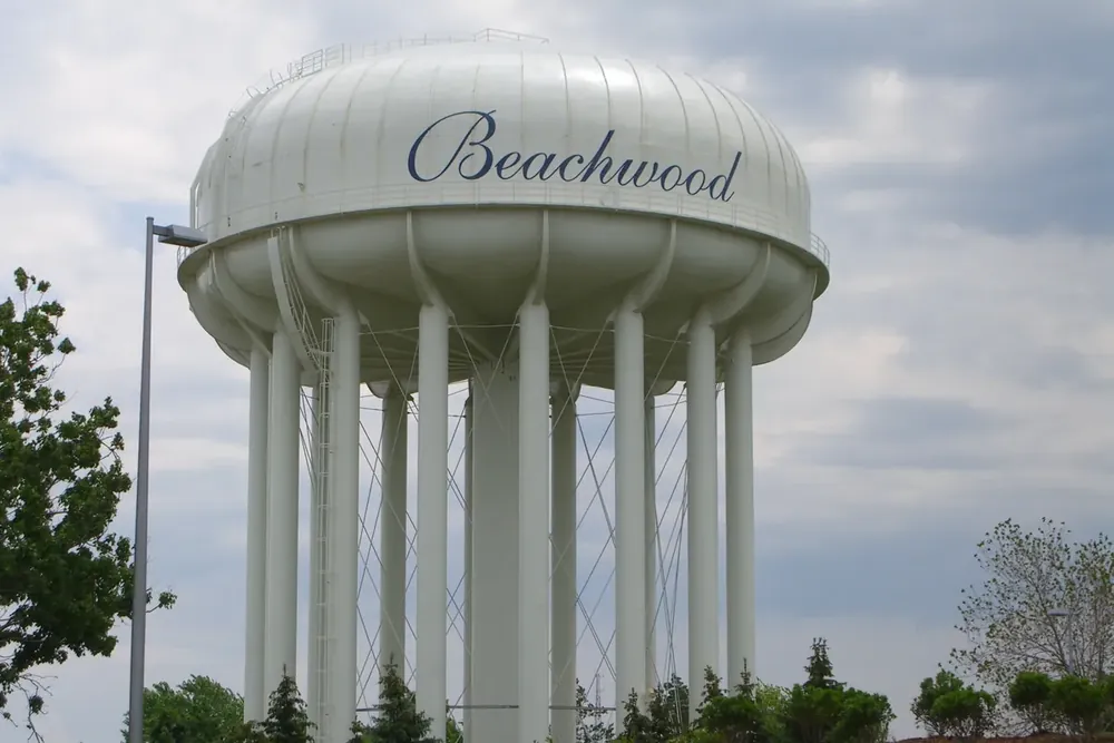 The white Beachwood water tower with the city name against a cloudy sky in Ohio