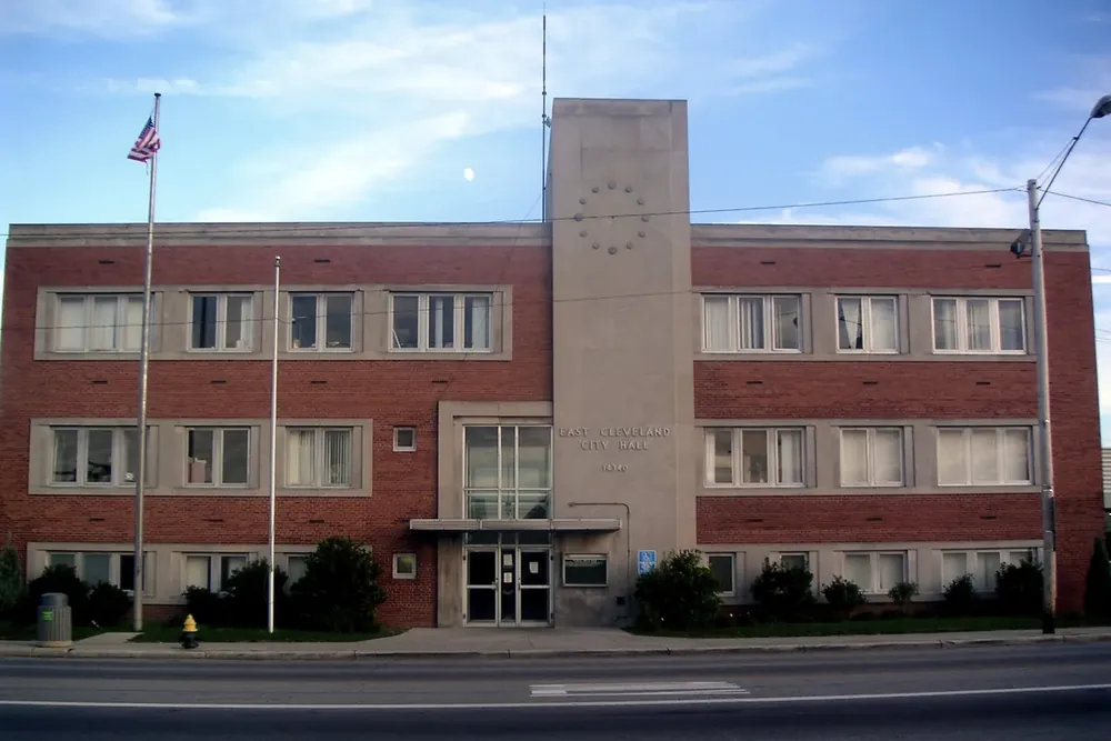 The brick East Cleveland City Hall with flagpoles along the street in East Cleveland, Ohio
