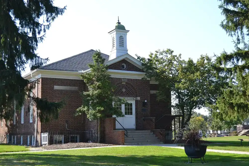 The brick North Olmsted Old Town Hall with a white cupola behind evergreens in Ohio