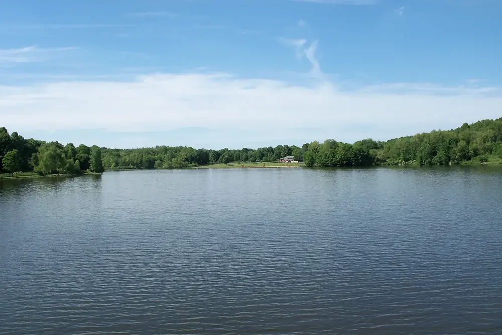 Silver Creek Lake surrounded by green woods under a blue sky in Norton, Ohio